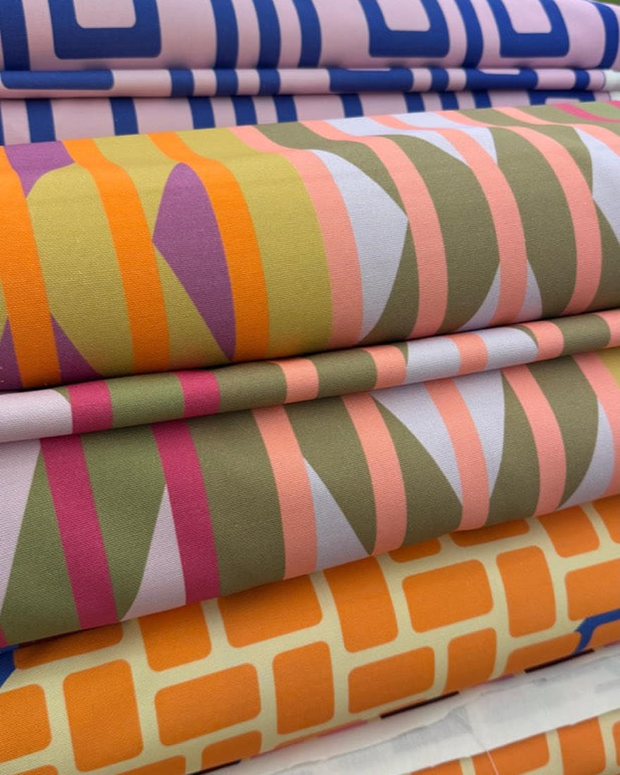 Rolls of printed cotton canvas stacked on a shelf
